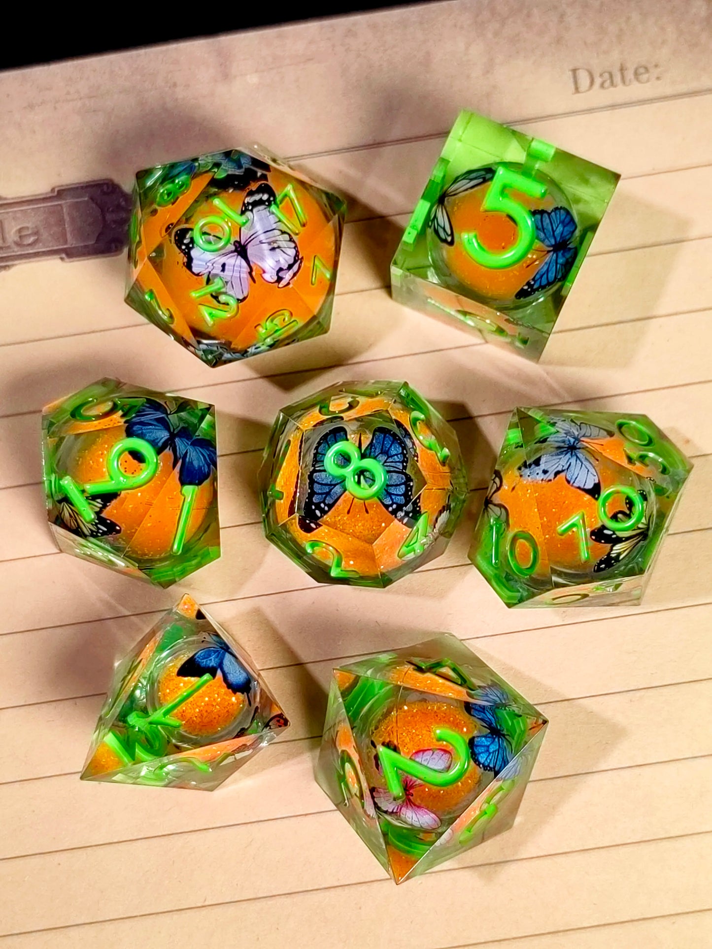 7 Piece Sharp Edge Resin Dice, Orange Sand Butterfly, Transparent with Green Numbers